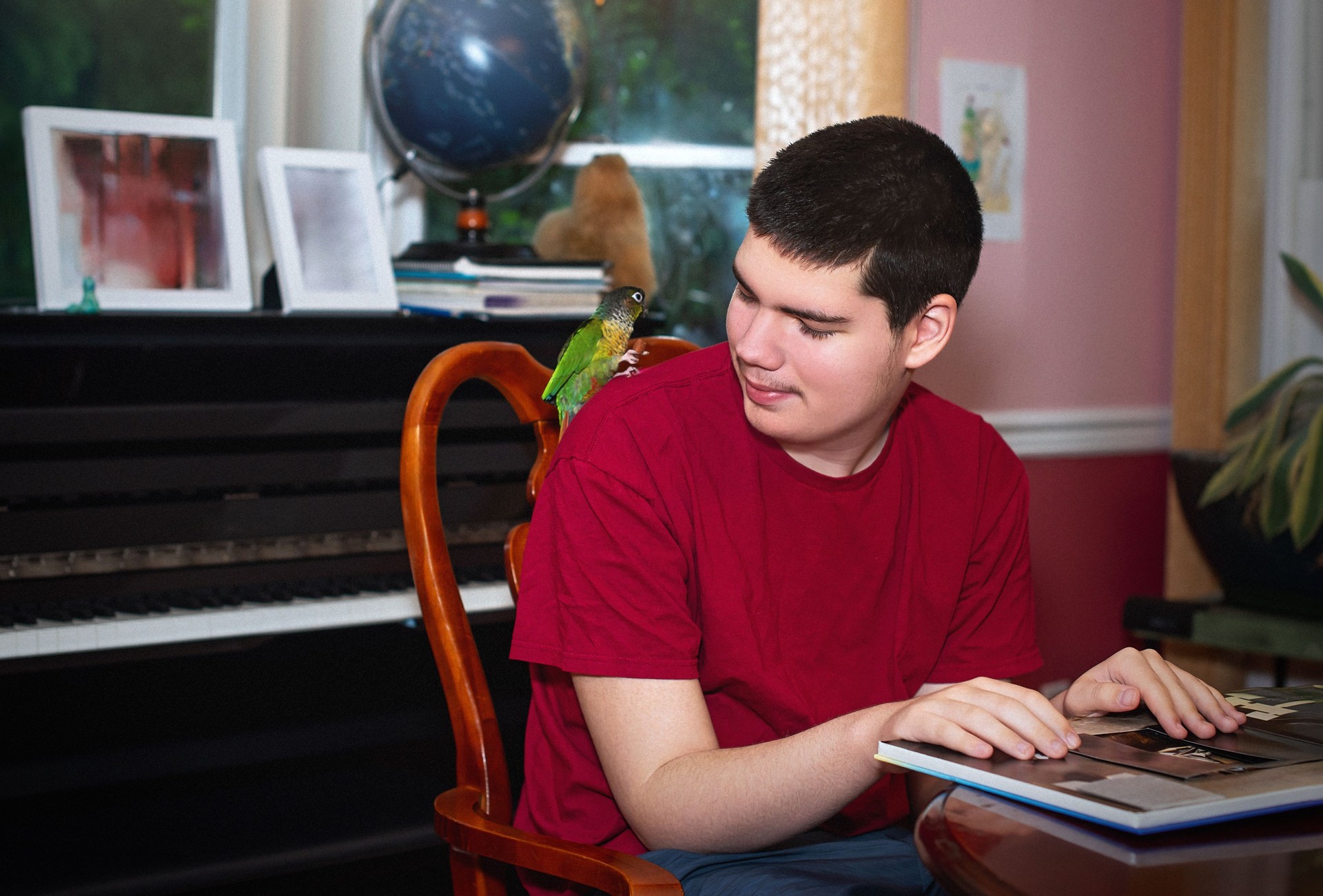 Autistic teenage boy with green-cheeked parakeet.